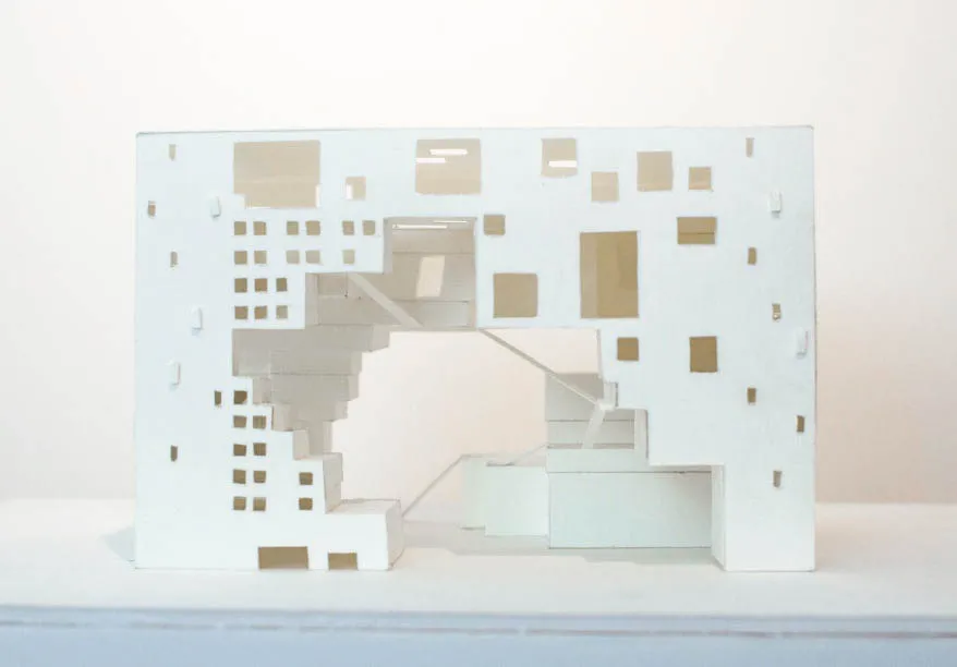 A plain paper model of the exterior facade of a rectangular building with an empty void in the middle