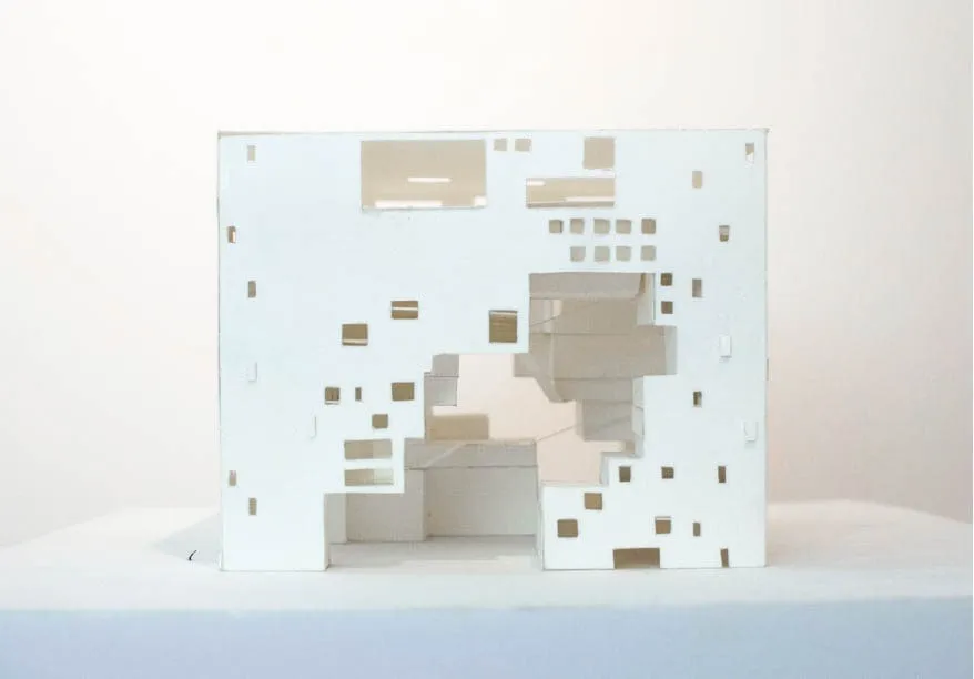 A plain paper model of the exterior facade of a rectangular building with an empty void in the middle