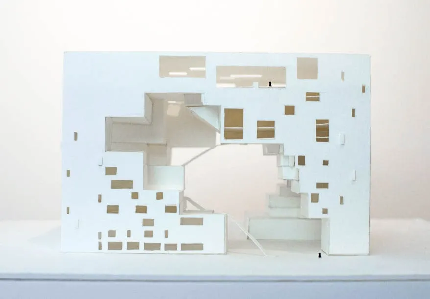 A plain paper model of the exterior facade of a rectangular building with an empty void in the middle