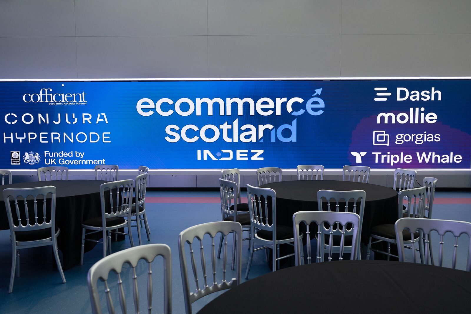 The Glasgow Science Centre atrium set with tables in front of the Ecommerce Scotland 2026 sponsor wall