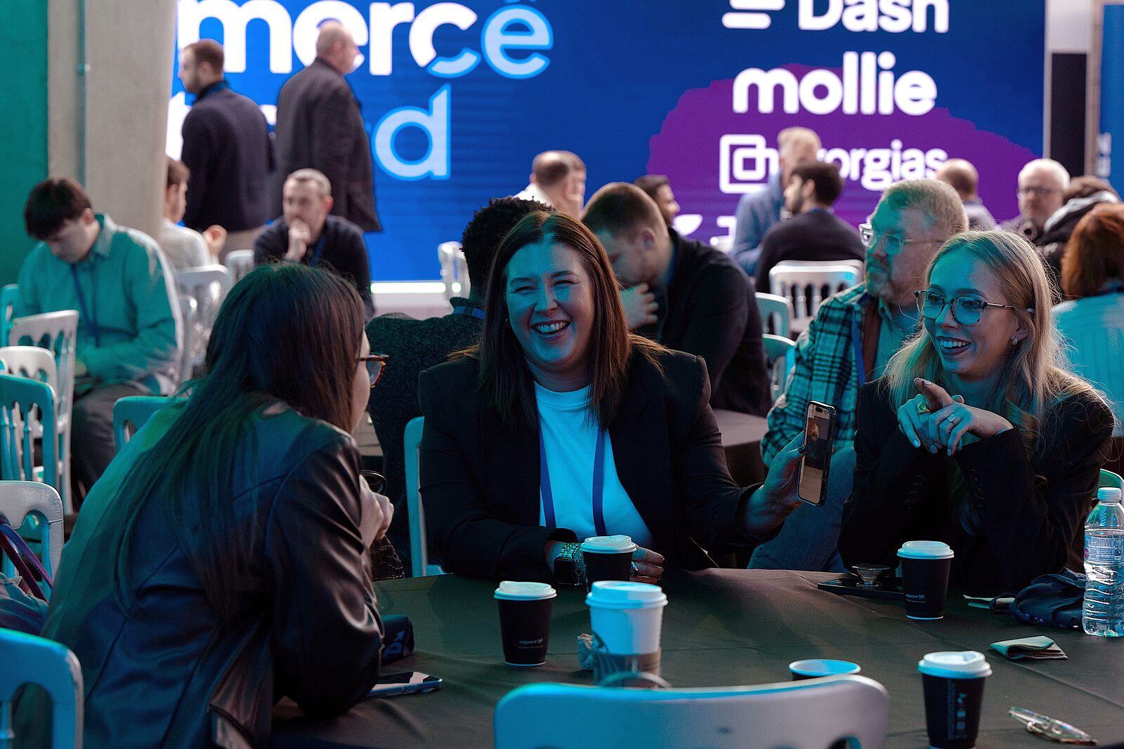 Attendees laughing together at a table in the Glasgow Science Centre atrium at Ecommerce Scotland 2026