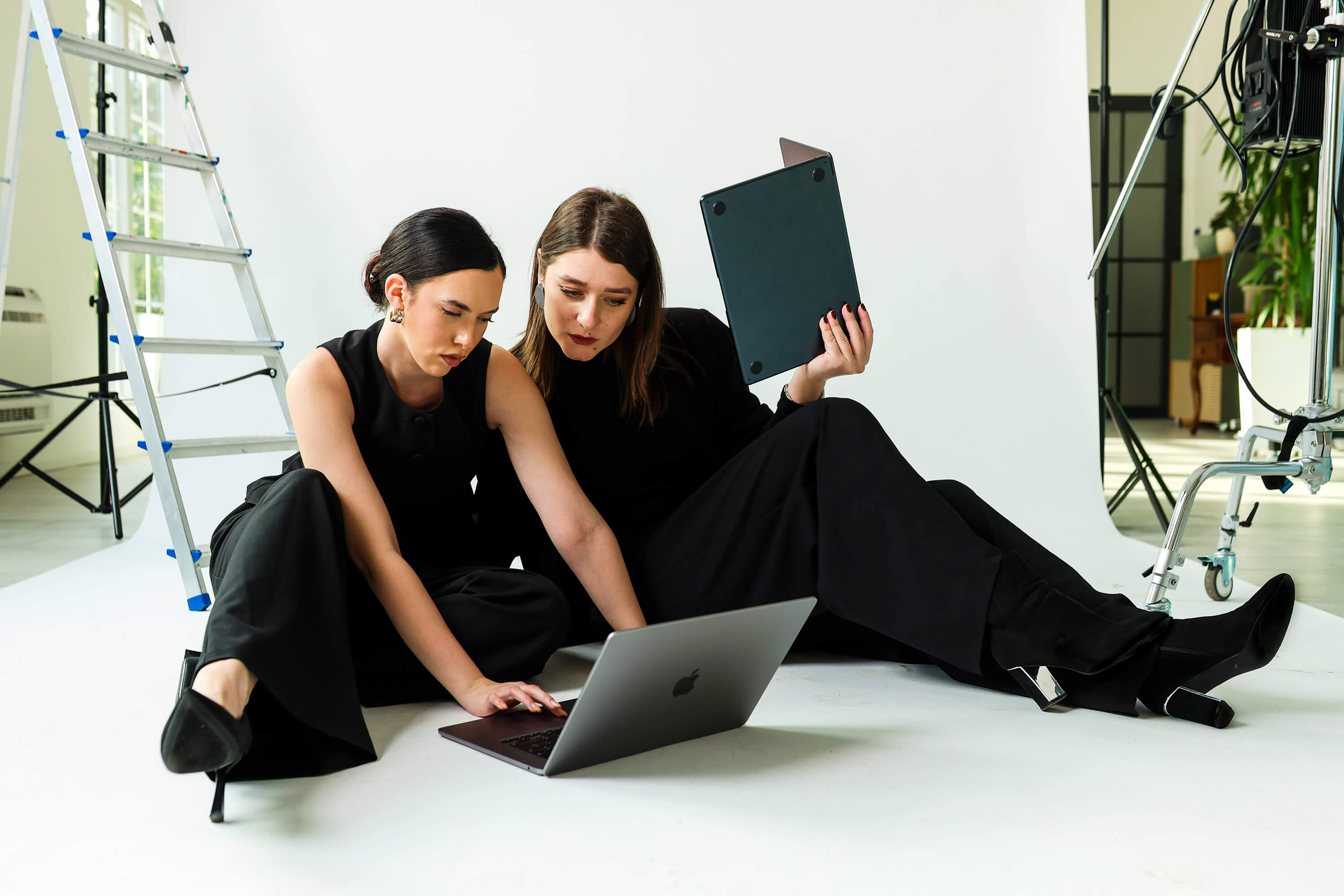 Group of four young adults posing indoors against a plain background, two women seated in front and two men behind them.