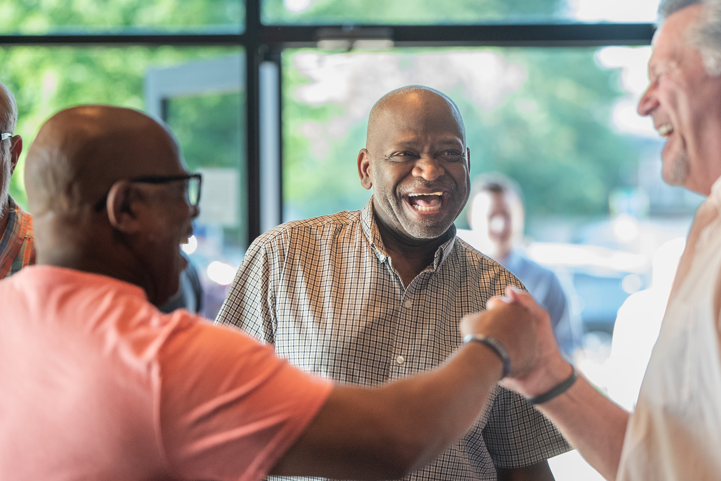 Image of three gentlemen laughing and catching up in the lobby of Church of the Harvest. 