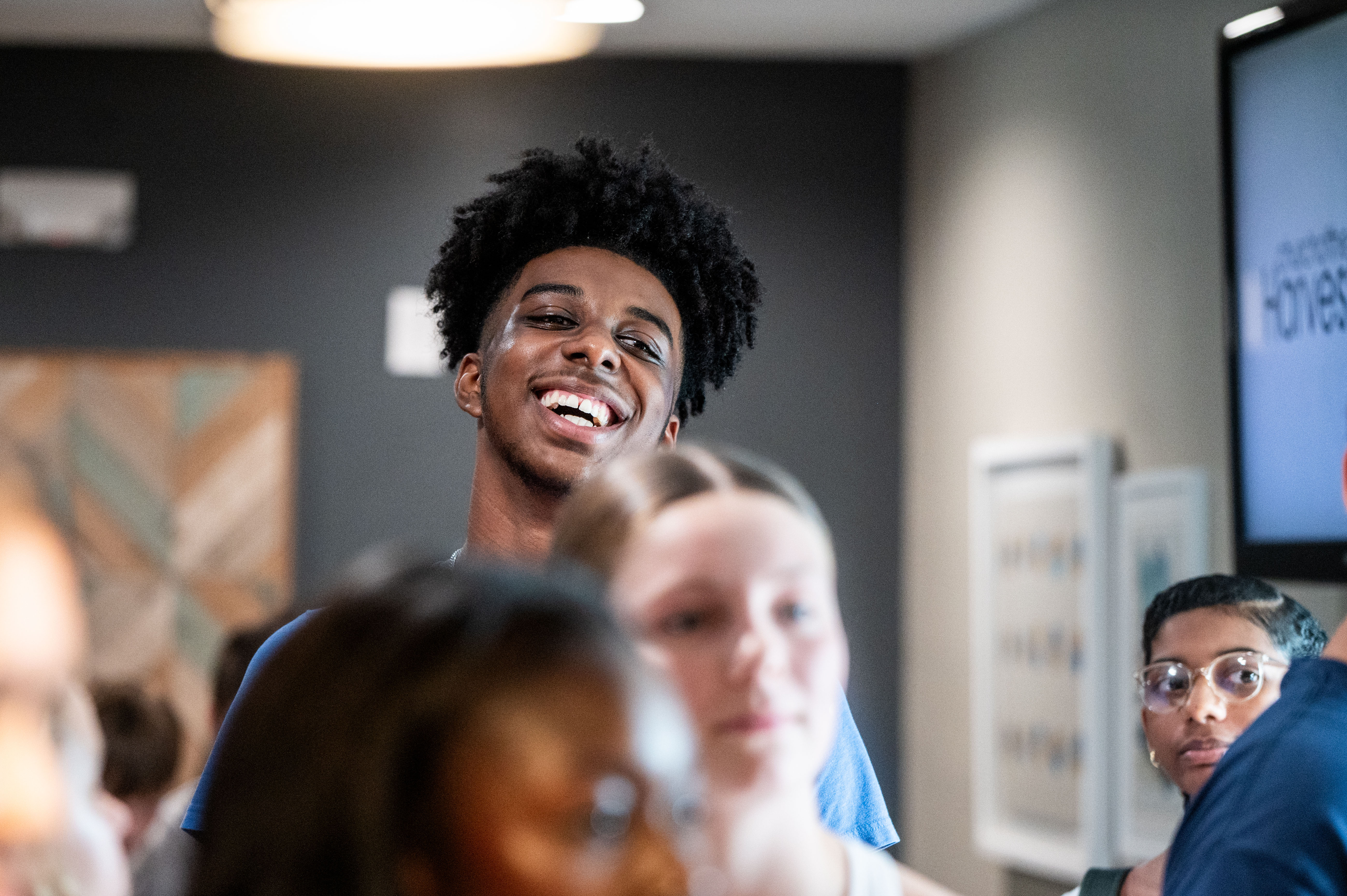 A tall young man smiling over the heads of his peers