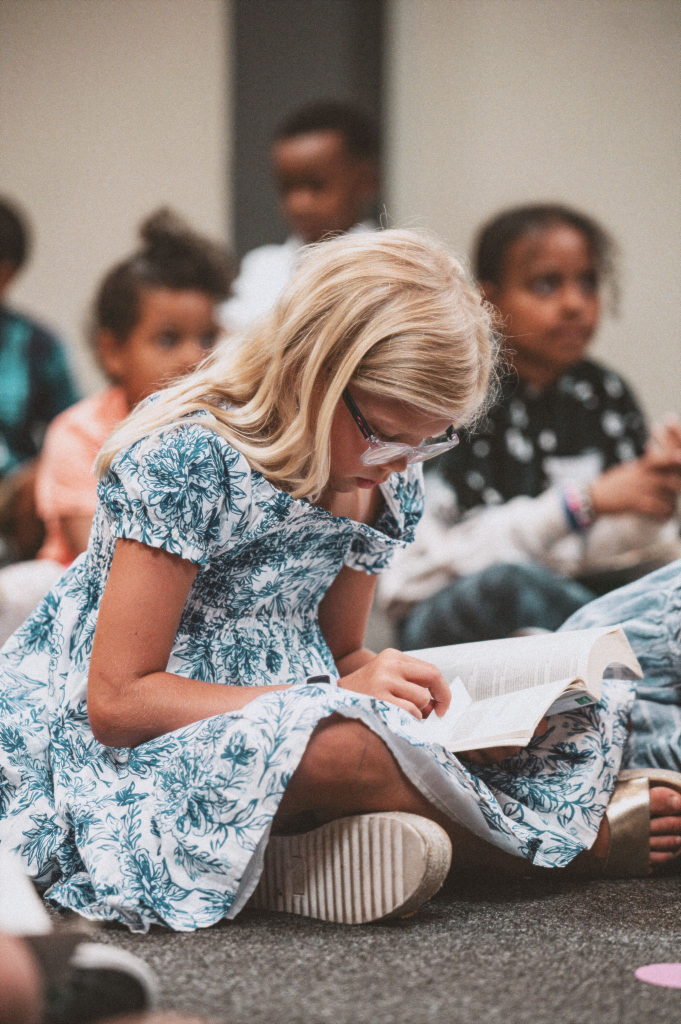 A little girl in Harvest Kids reading along in her Bible during the lesson