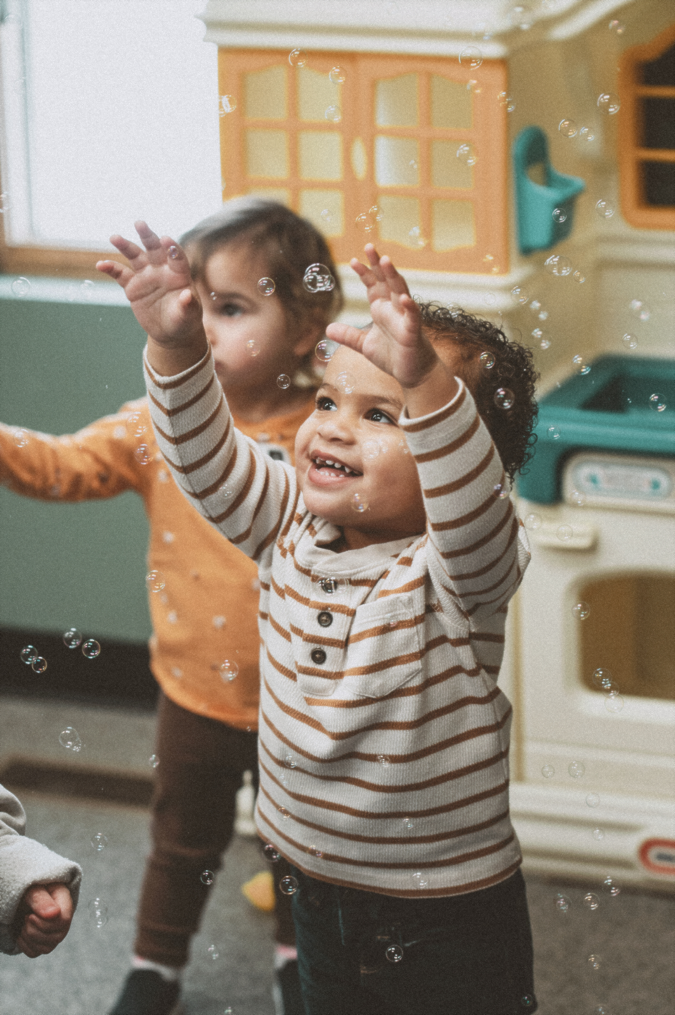 Two young kids chasing bubbles 