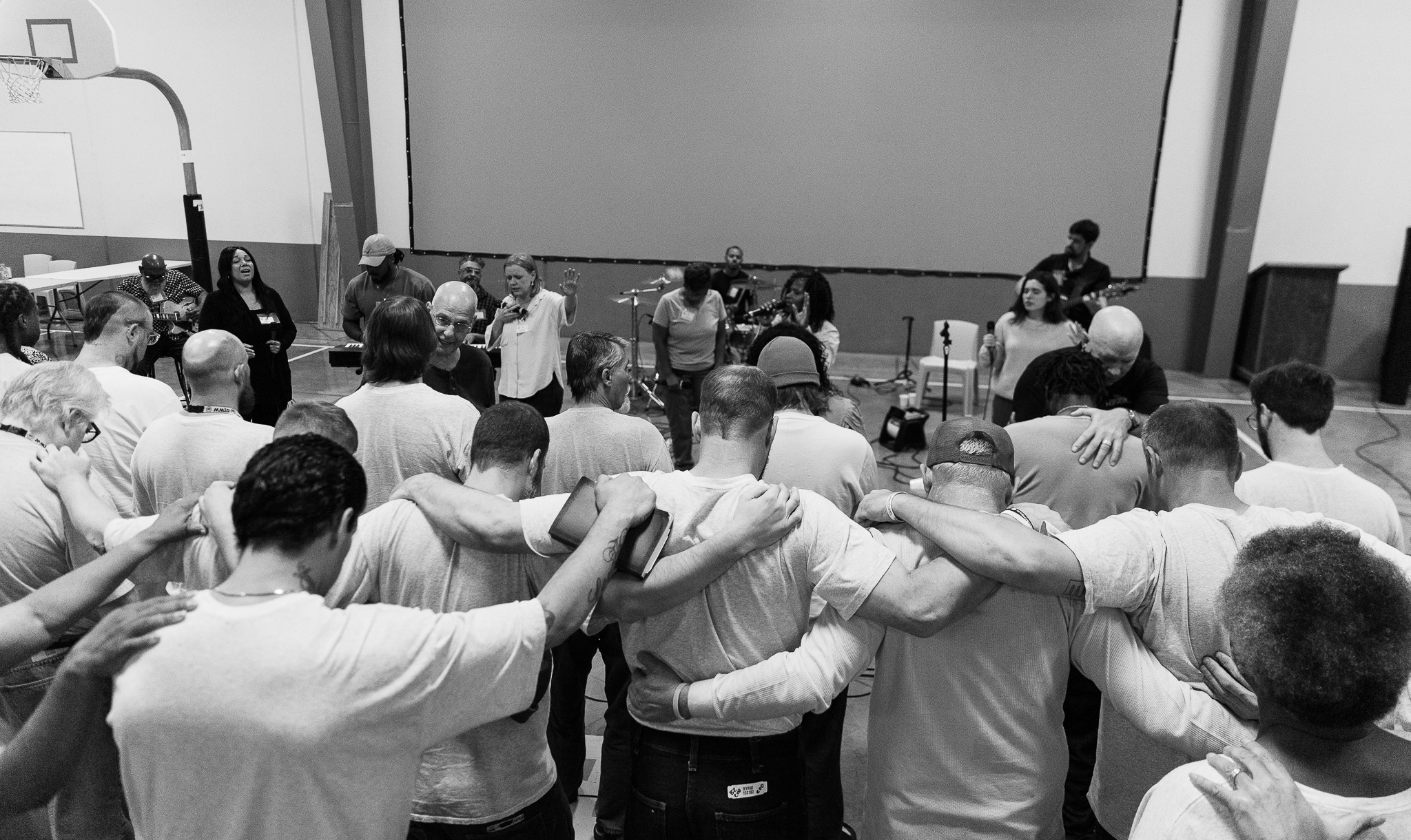A large group of inmates linking arms in prayer