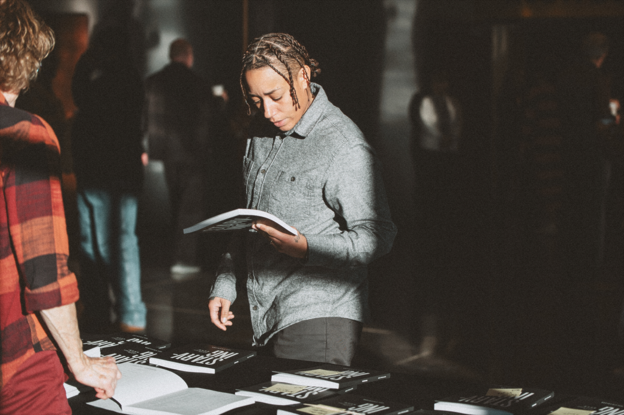 A person stands at a table looking through printed church materials in a softly lit room.