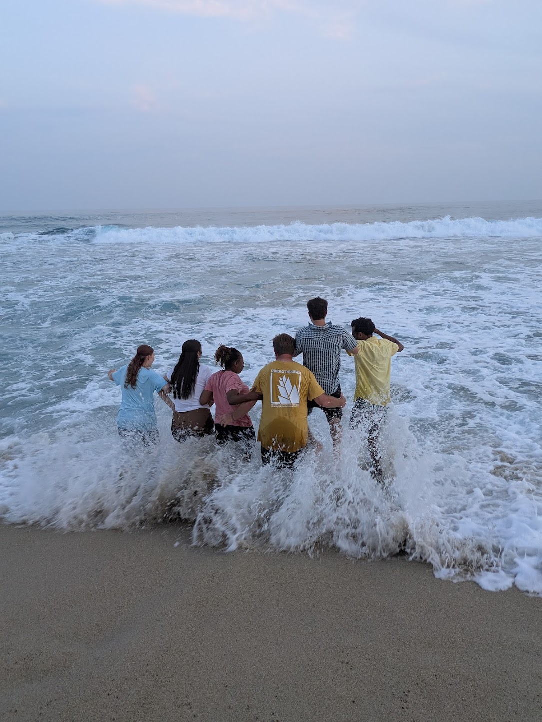 A group of youth running into the ocean in Roca Blanca