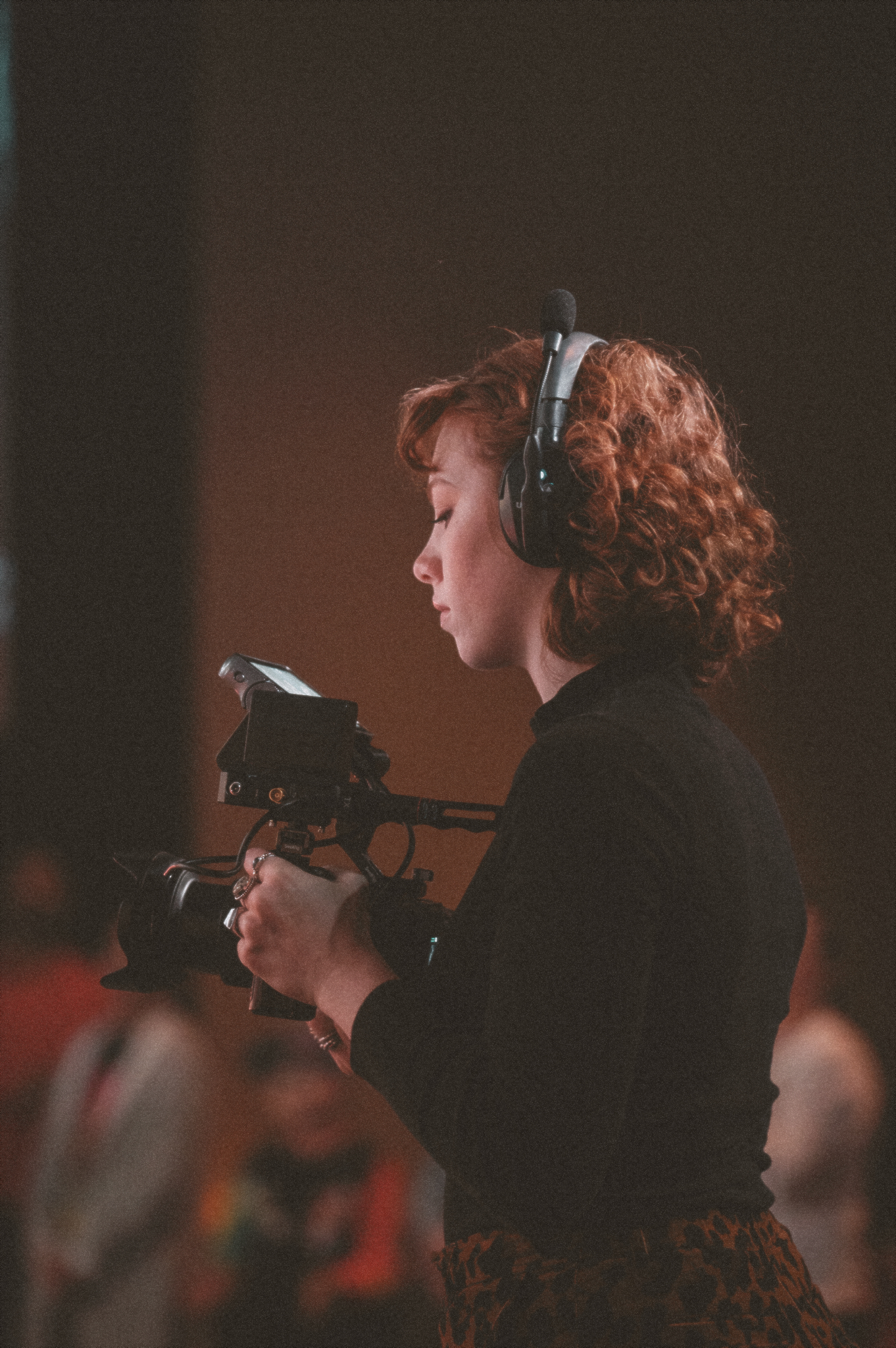 A young woman with red curly hair wears large headphones as she records service