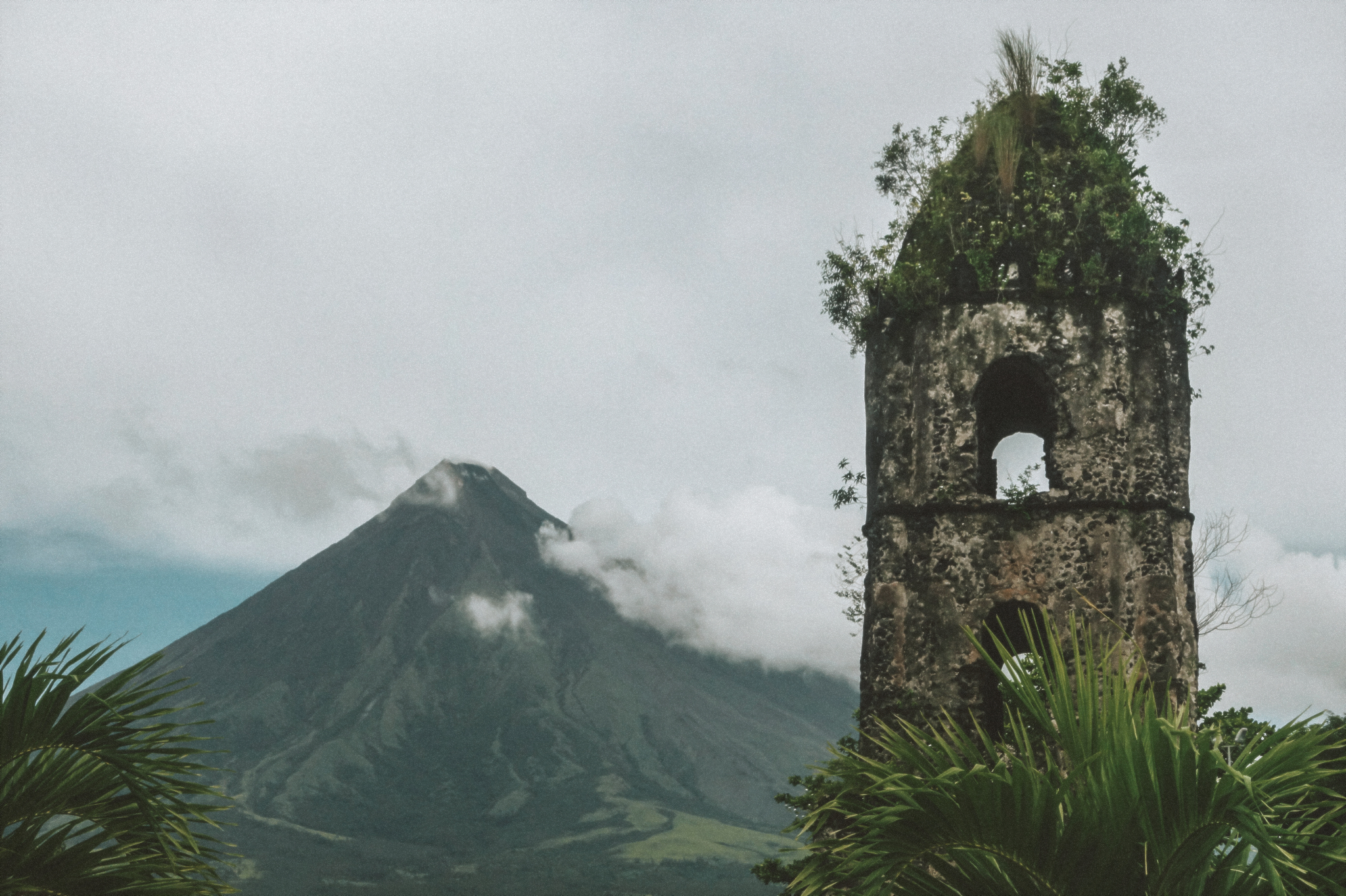 An old, historic, abandoned church steeple in the midst of a lot of overgowth and greenery with a view of the mountains in the background in the Philippines. 

Credit: camille-san-vicente-Z5xHpUH9o8Y-unsplash.jpg