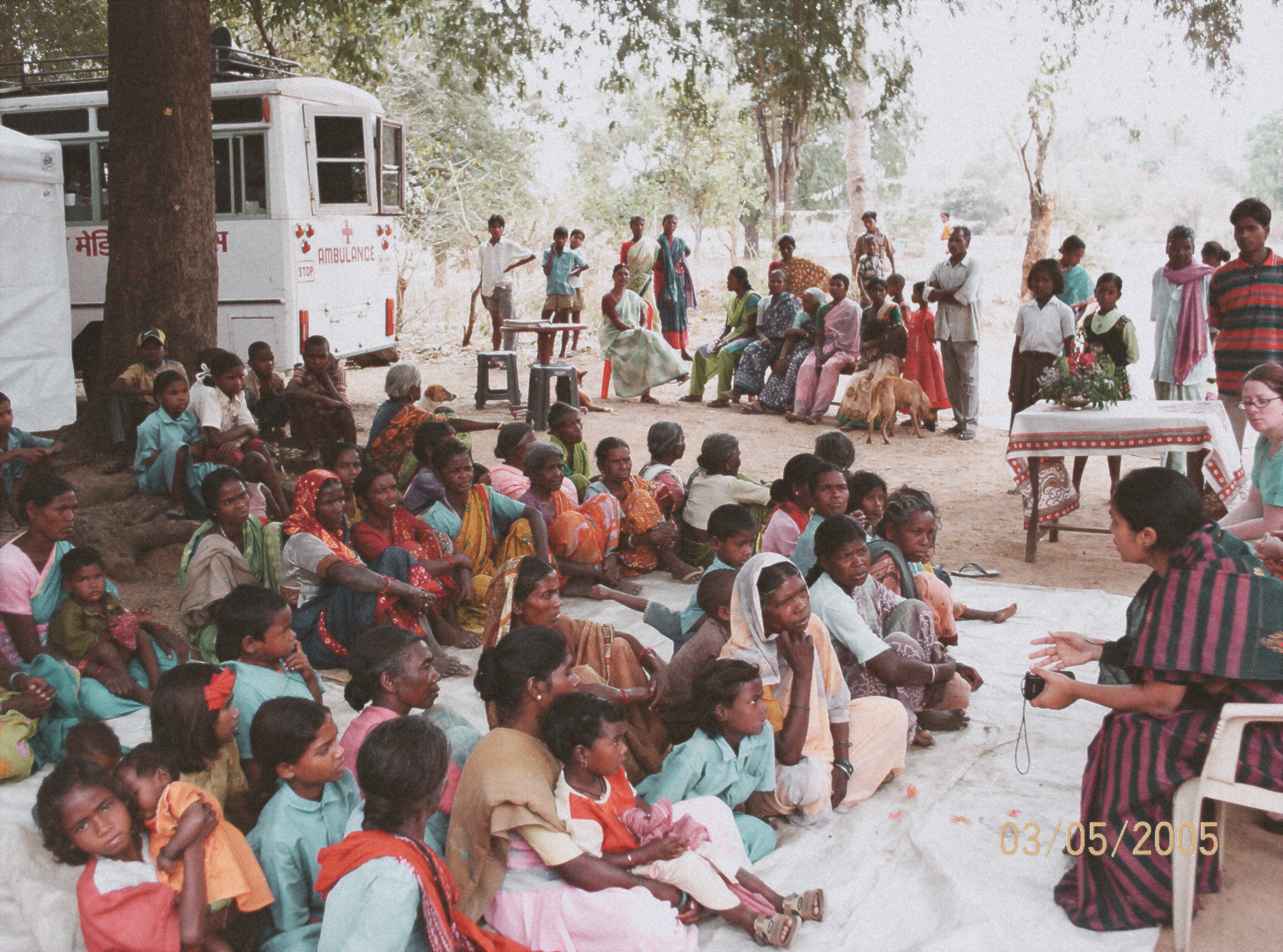 A woman reaches to a group of men, women and children during outreach time in India