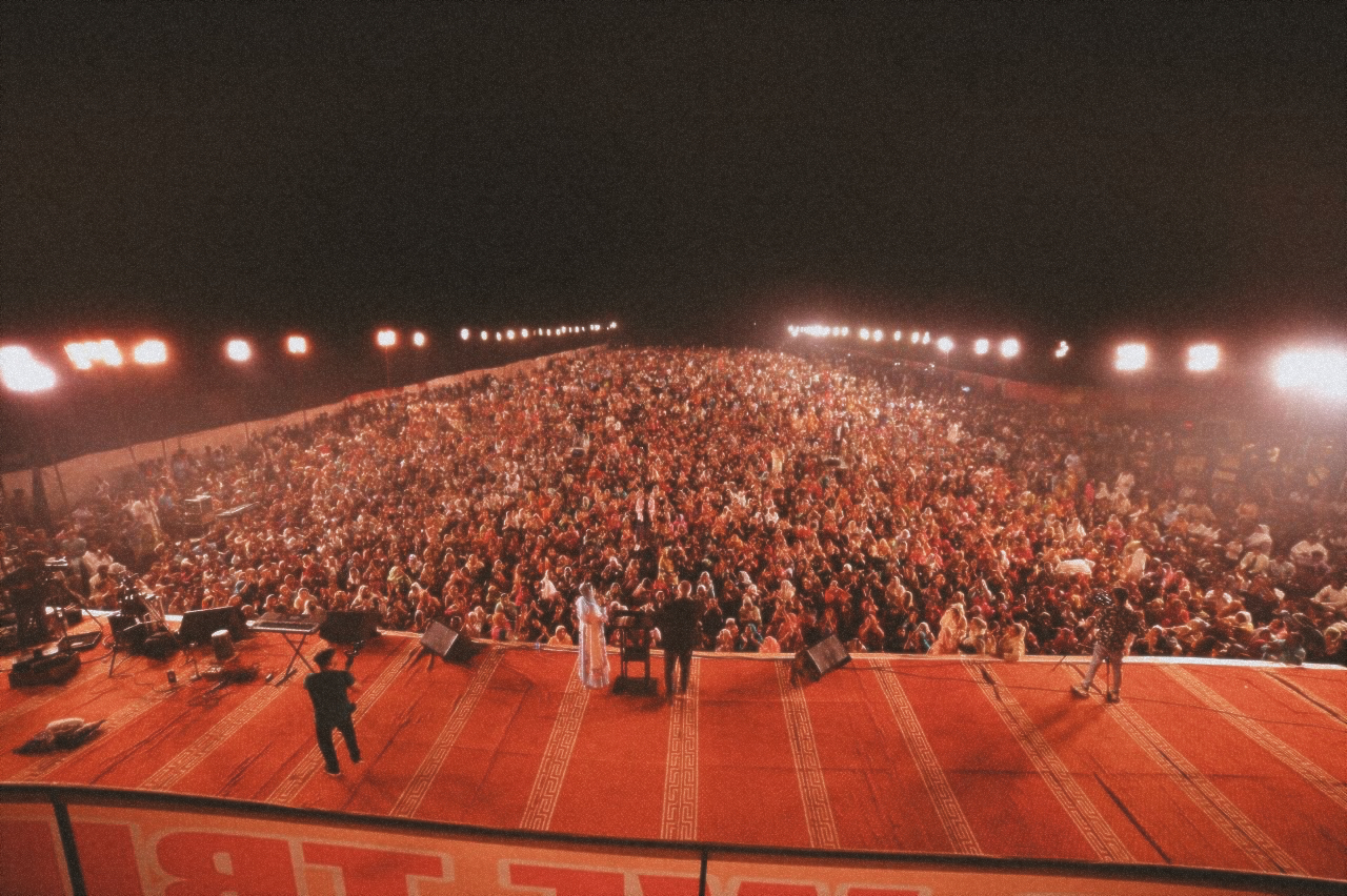 An aerial view of a crowd of ten thousands and red carpeted stage. 