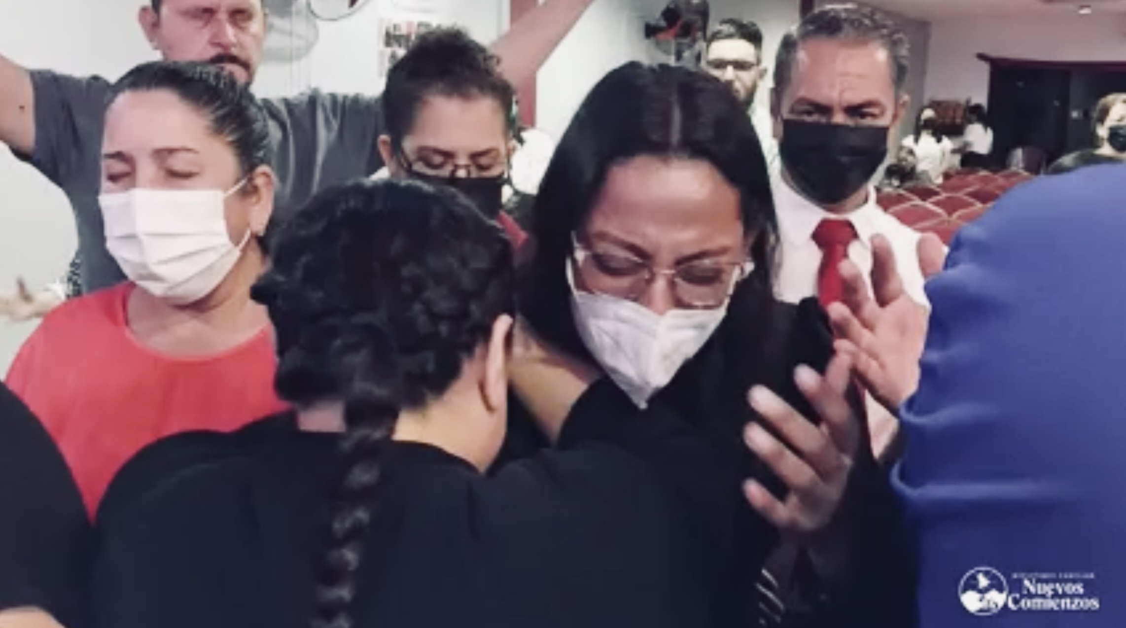 A woman praying over another woman in a mask during a prayer meeting in Honduras