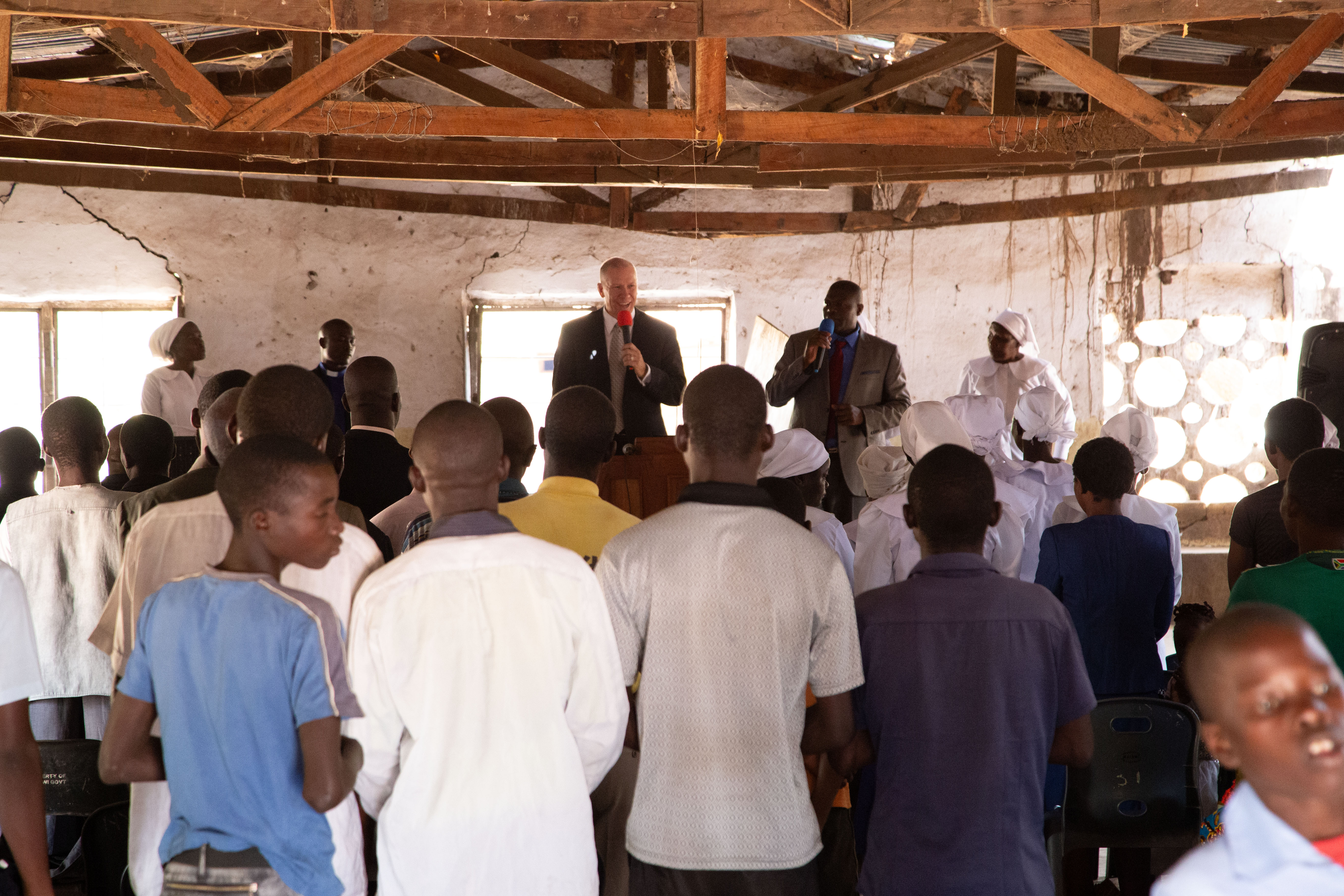 Congregation gathered inside a rustic church building as Pastor David addresses the audience from the front during a worship service.
