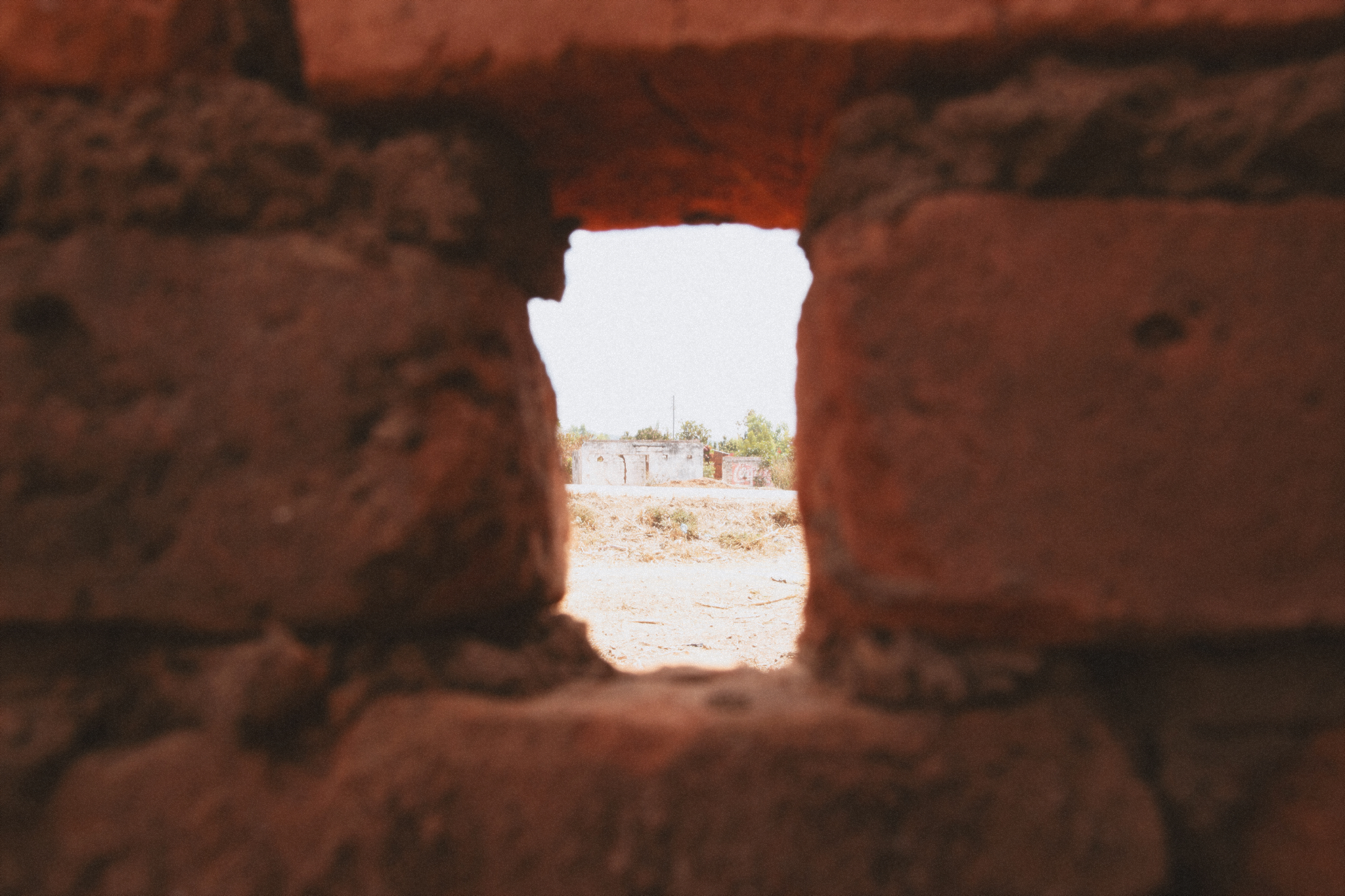 A hole through a brick wall frames the image of a small town. 