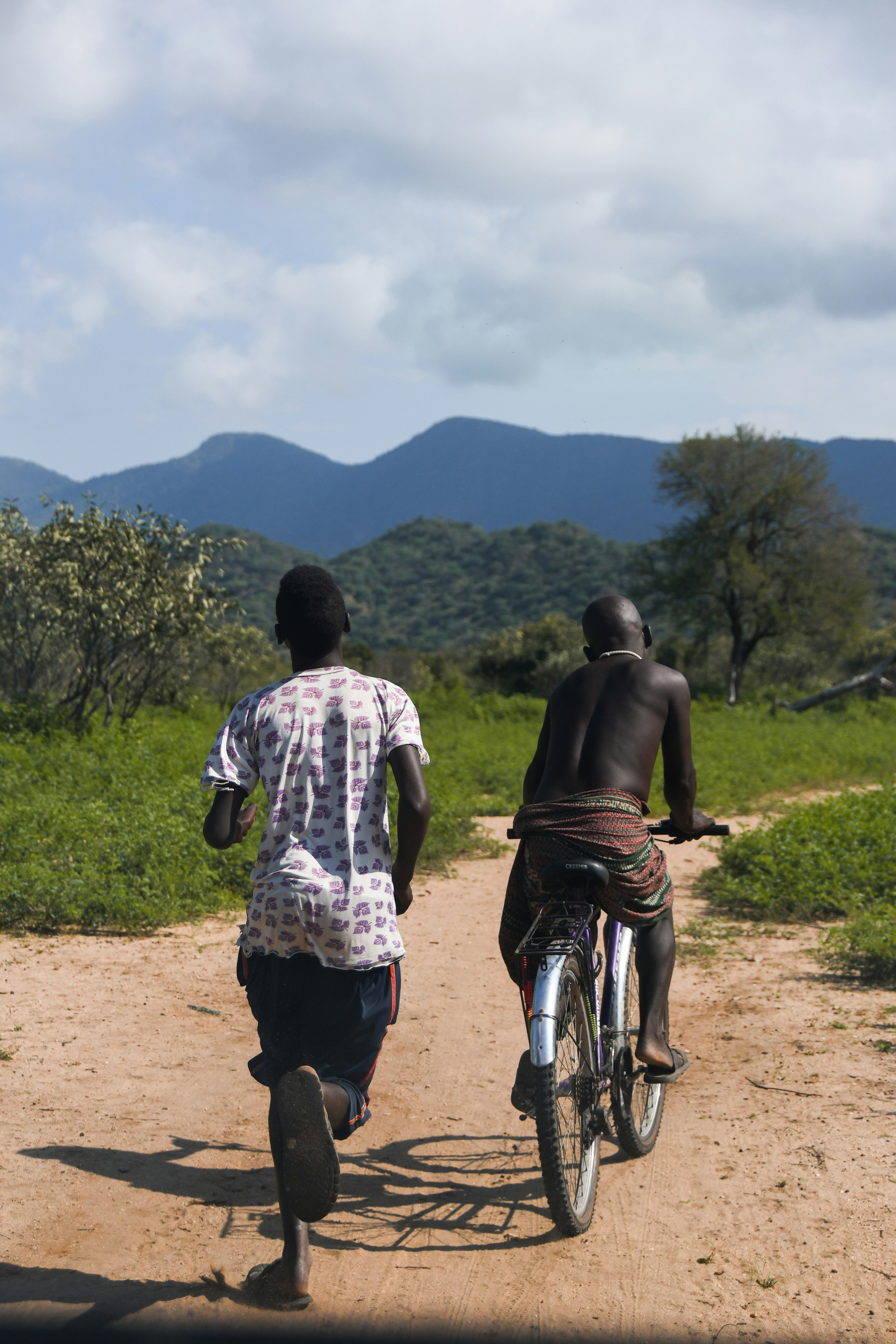 An Ethiopian man rides his bike down a dirt road with a friend running alongside him. 

Credit: taylor-flowe-efOD1uIR8ic-unsplash