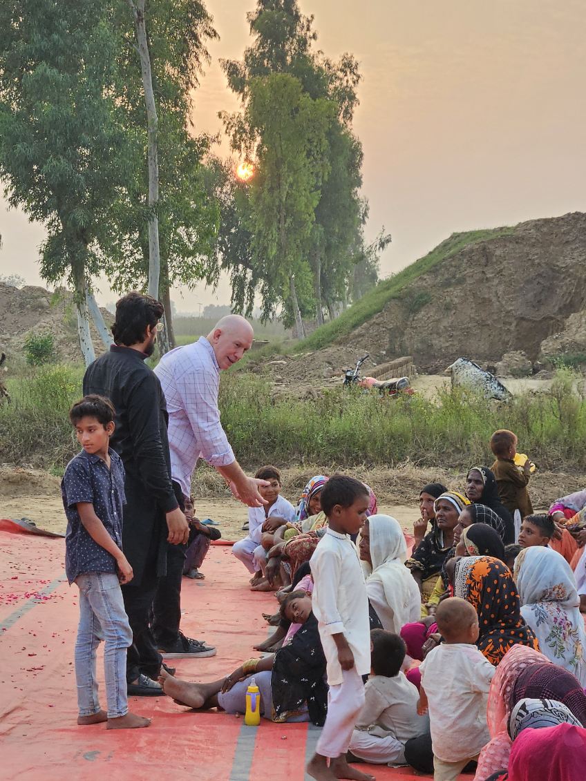 Pastor David ministers to children in the brickyards in Pakistan, his translator stand nearby to assist. 