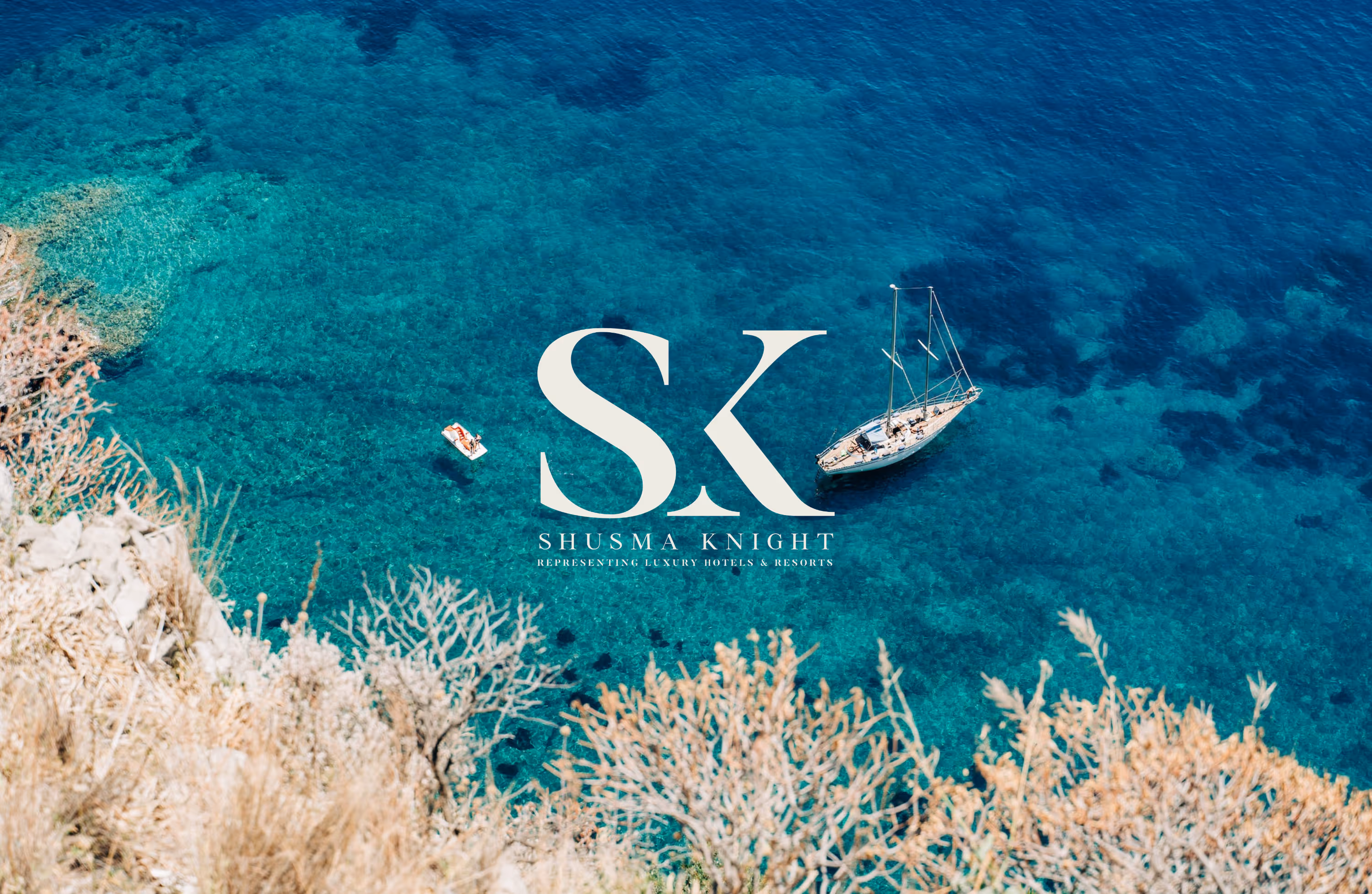 A costal setting with clear blue waters. A small sailing boat is anchored up. The logo for Shusma Knight sits in the middle of the image.