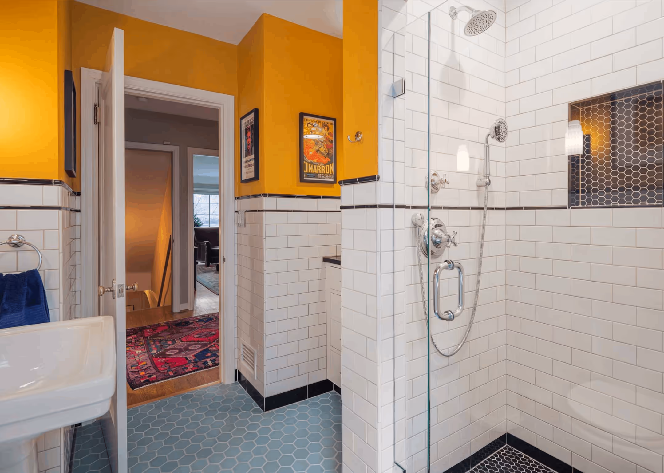 Bright bathroom with yellow upper walls, white subway tiles, hexagonal blue floor tiles, and a glass-enclosed shower with chrome fixtures.