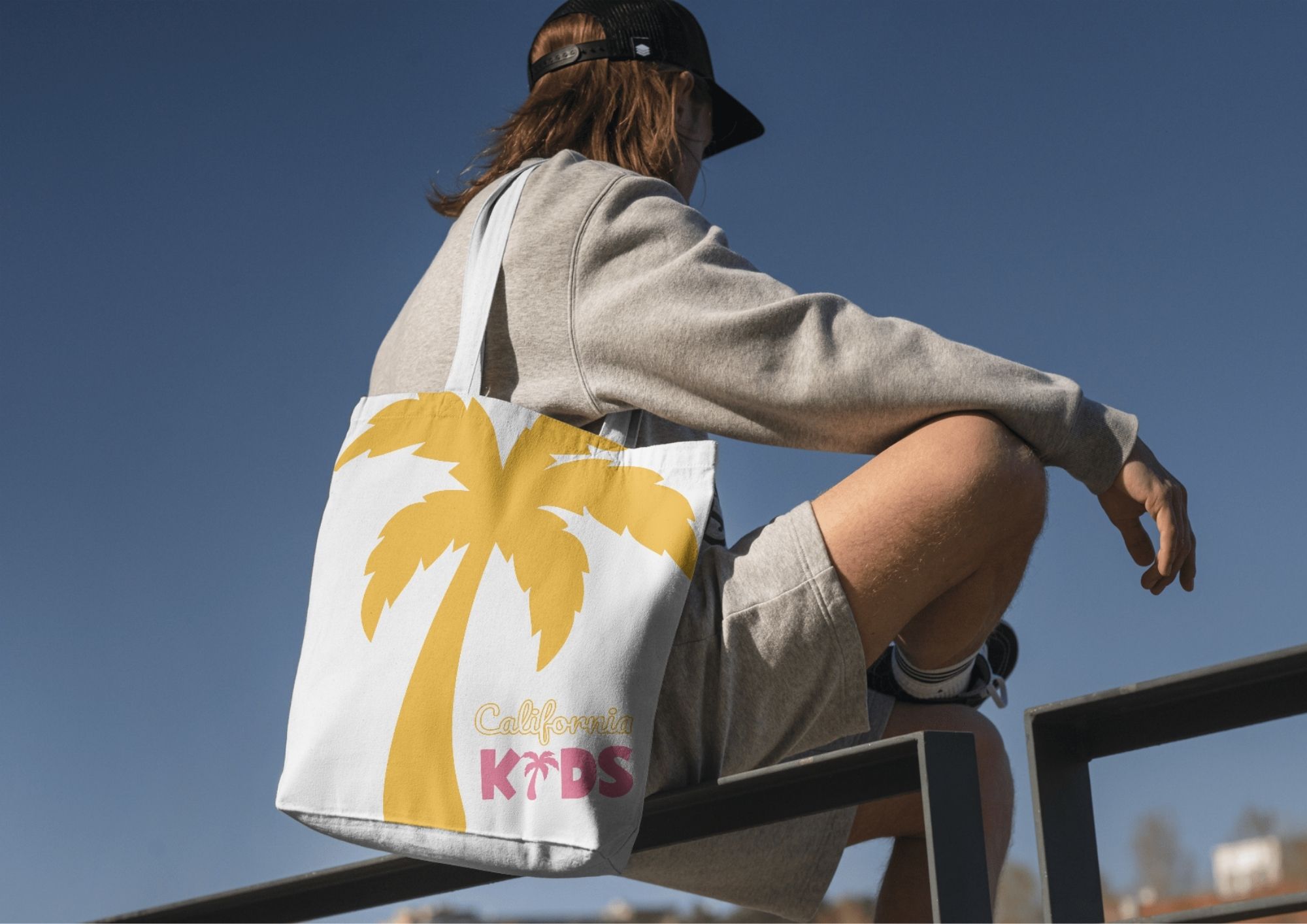 Mockup d’un tote bag California Kids aux couleurs de l’identité visuelle créée par l’agence Bizbold à Liège.