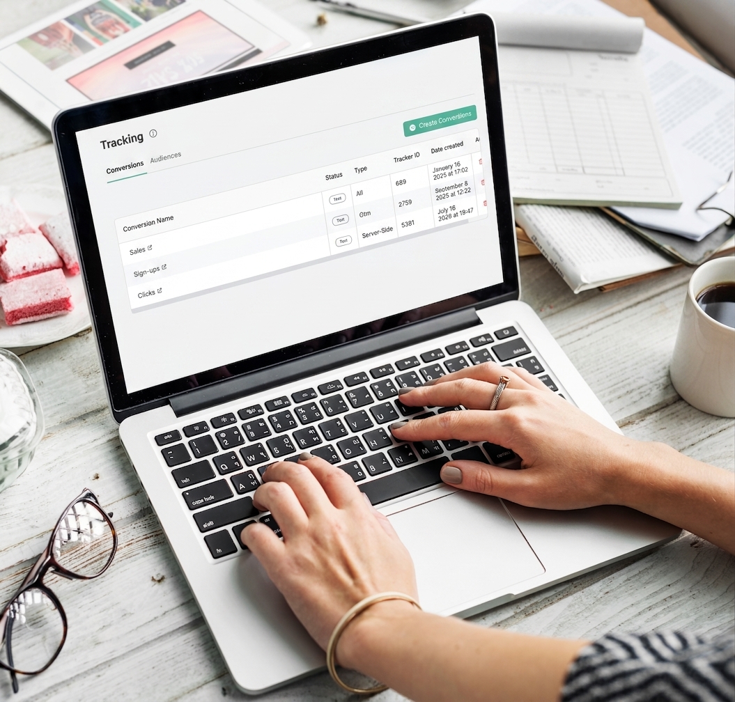 A woman using the 'Tracking' dashboard application on a laptop to manage conversions and audiences.