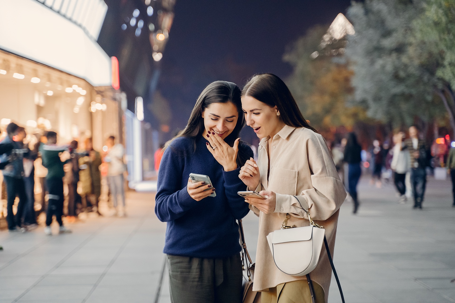 Two people discovering content on a phone in a city at night