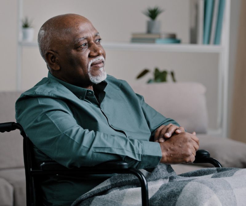 Elderly man sitting at home with a caregiver offering support, symbolizing aging, independence, and assisted living needs. Milford elder law