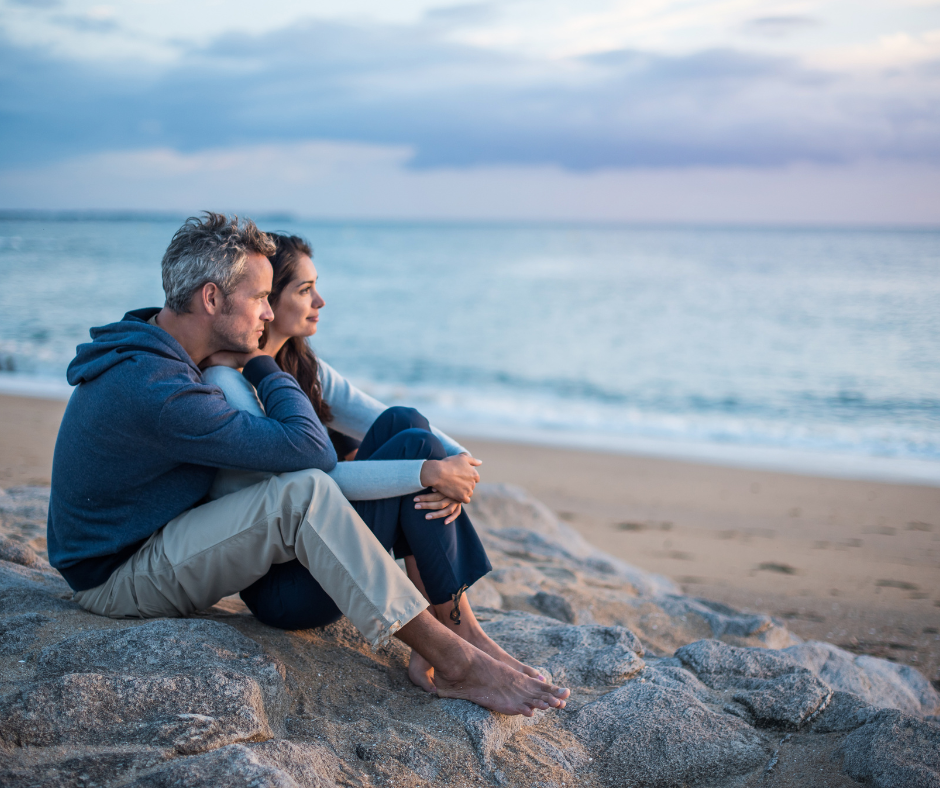 couple sitting at beach at sunset - Milford estate lawyer concept
