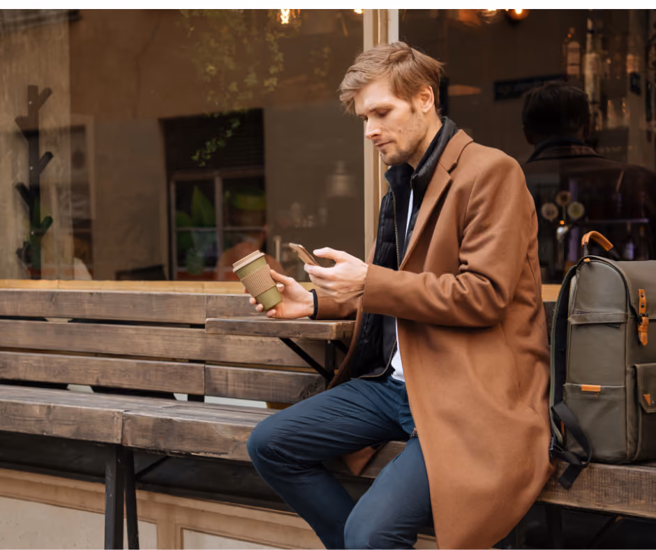 man with coffee cup looking at phone on bench - Trumbull Estate Attorney concept