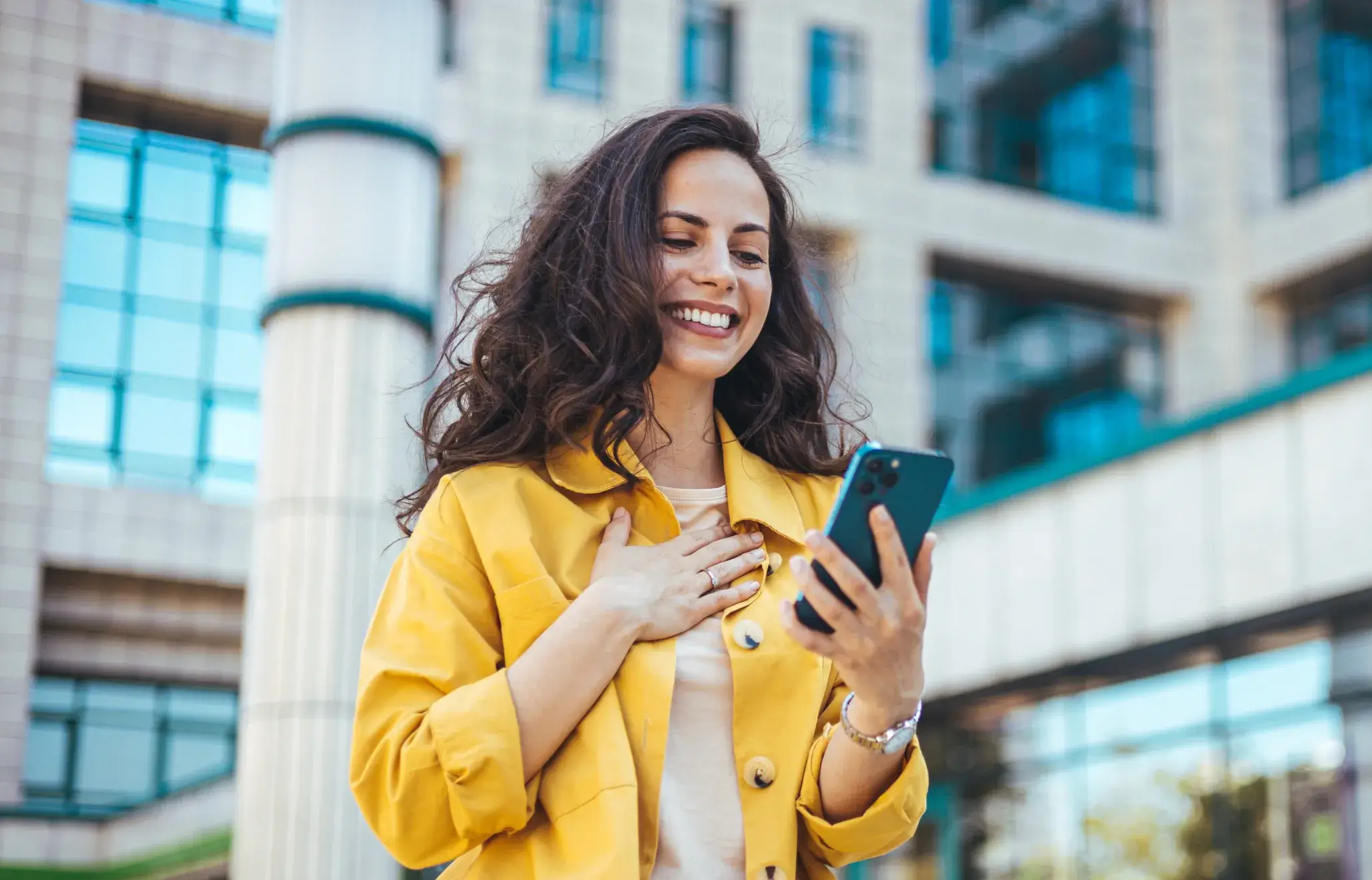 a woman in a yellow jacket looking at her cell phone