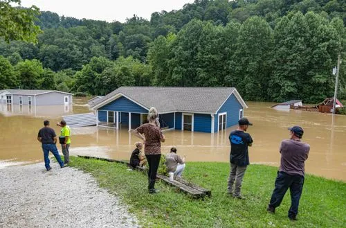 People observing flood damage with houses submerged in water.