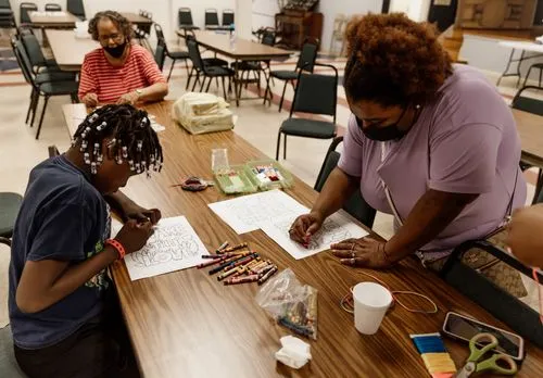 Children and adults coloring and crafting at a community event.