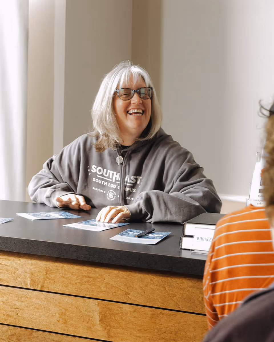 Smiling woman sitting in a church pew during a service.