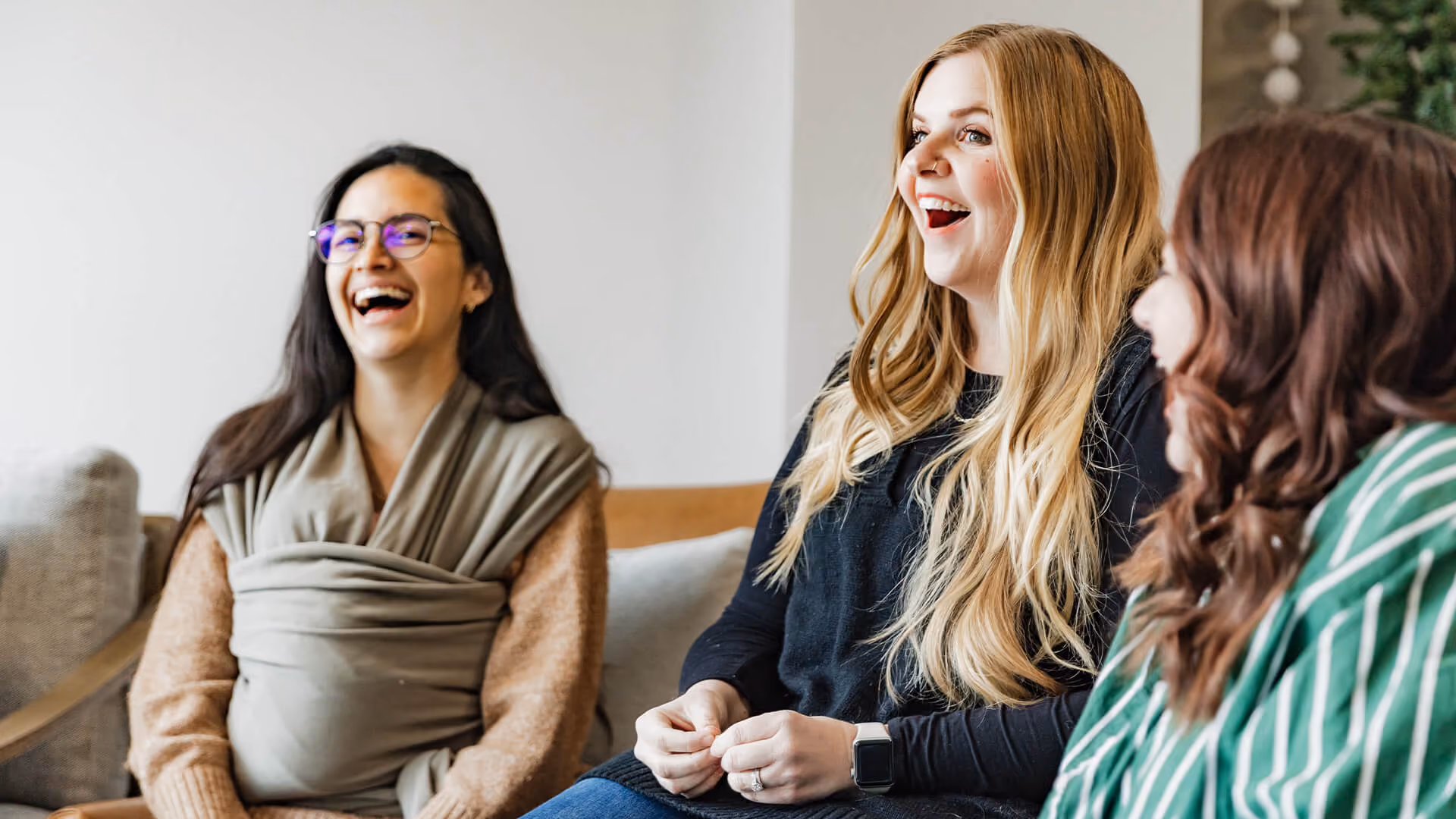 Two people sitting at a table during a home group, laughing and writing.