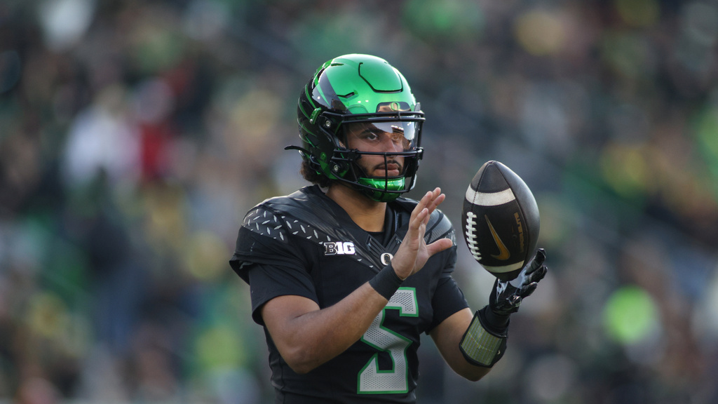 Oregon QB Dante Moore throws a football in a CFB game.