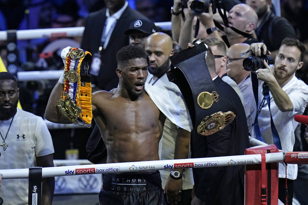 Britain's Anthony Joshua holds the title belts after winning a boxing match.