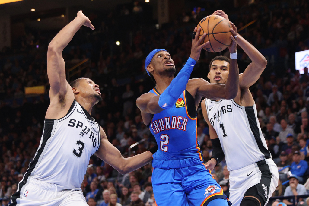 Oklahoma City Thunder PG Shai Gilgeous-Alexander jumps against San Antonio Spurs C Victor Wembanyama and F Keldon Johnson.