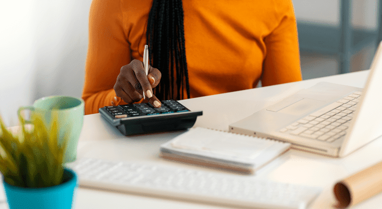 Woman sitting at a laptop computer using a calculator
