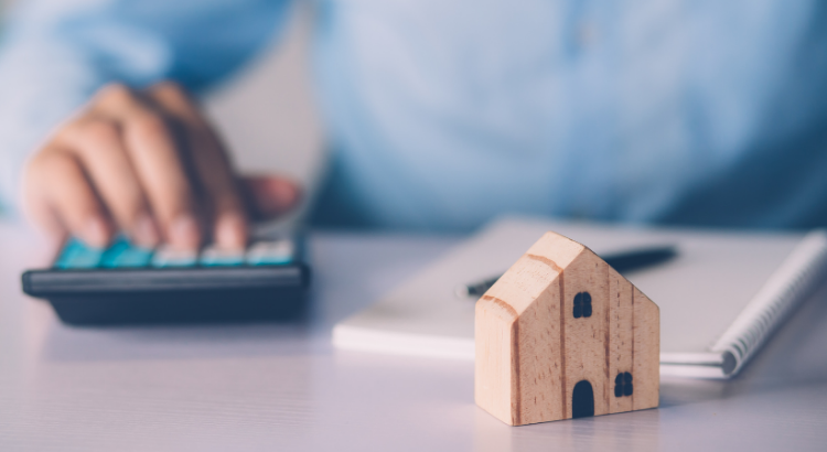 A small wooden house and a person using a calculator