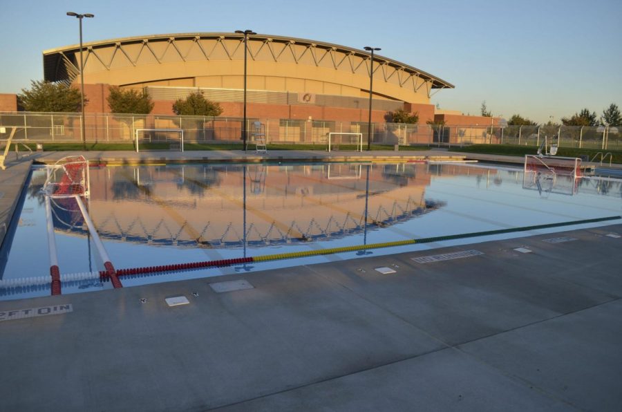 Outdoor pool in front of a school gym at sunset