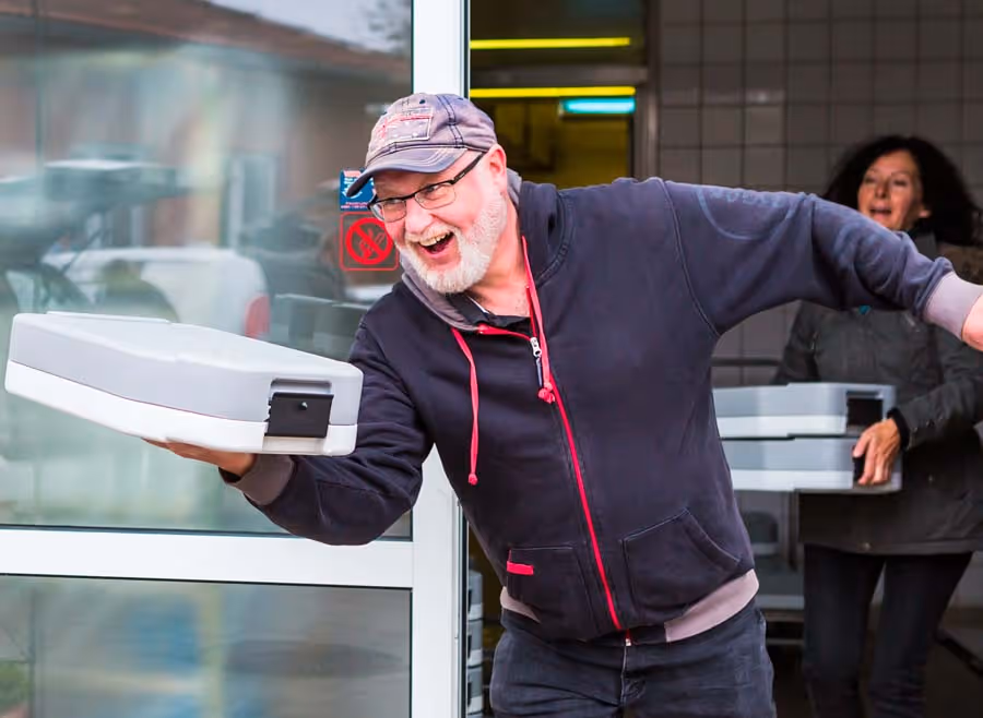Essen auf Rädern - der gut gelaunte Fahrer auf dem Weg zu seinem Auslieferungsfahrzeug.