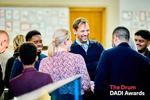 Colleagues engaged in animated discussion and joyful celebration upon receiving a Dadi Award nomination.