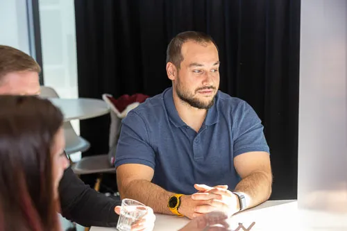 An individual intently listening to colleagues speaking, displaying attentiveness and engagement.