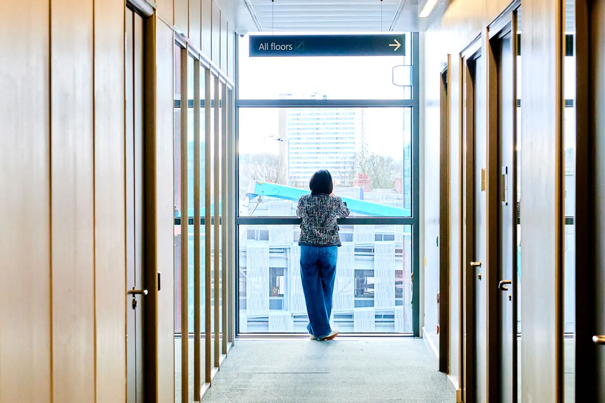 A Leighton colleague stood near a large window, taking a phone call whilst looking out at Newcastle city centre.