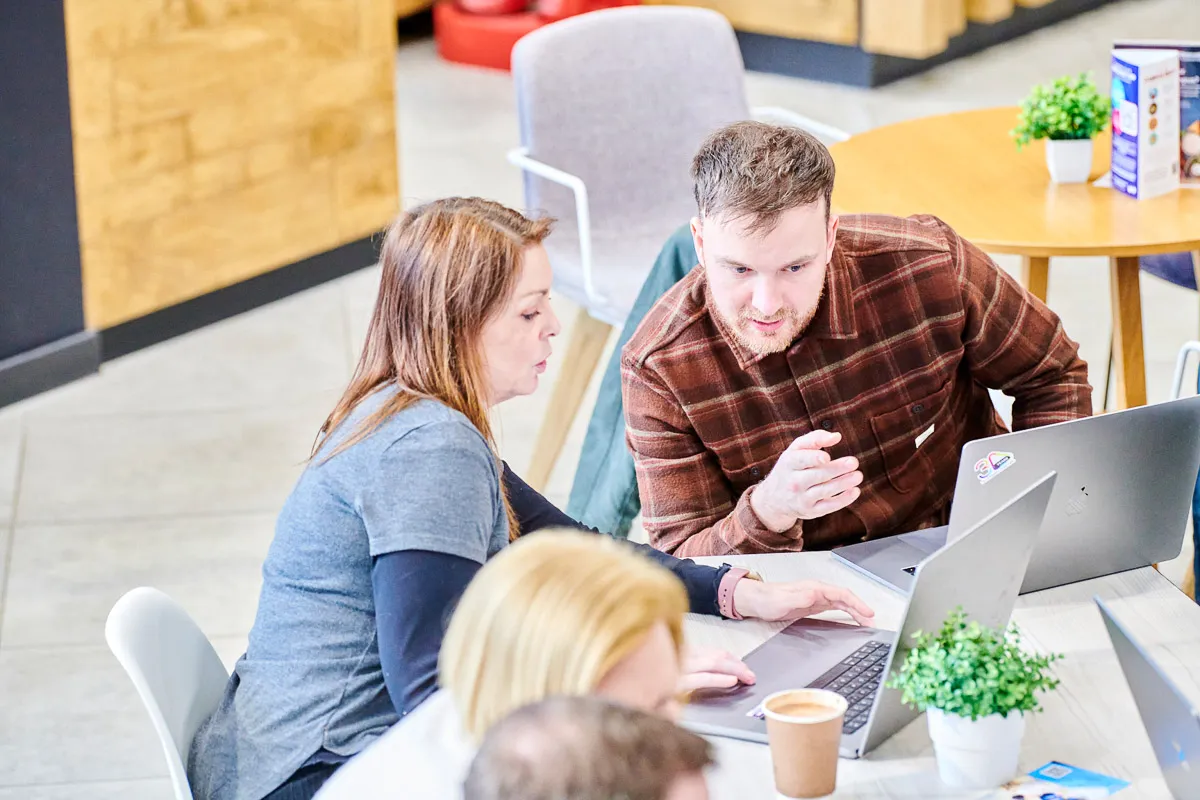 Leighton colleagues huddled around a laptop, collaborating on a project.