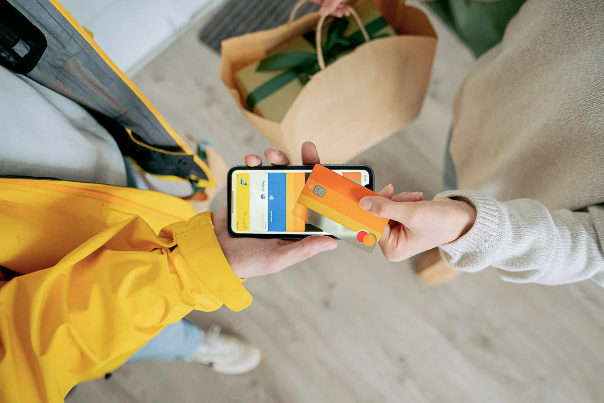 A bird's-eye view capturing a smartphone held over a payment terminal, illustrating a contactless payment transaction in progress.