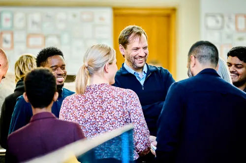 Six Leighton colleagues, stood up talking together. 