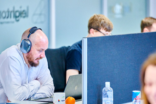 A Leighton colleague, in an office setting on a meeting wearing headphones. 