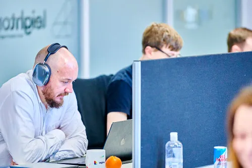 A Leighton colleague, in an office setting on a meeting wearing headphones.
